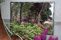 Hampton Court Flowershow 2009, The Sadolin Nature to Nuture Garden designed by Philippa Pearson.  Astilbe chinensis 'Vision in Red' growing beside metal sculpture reflected in mirror behind.