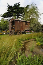 Hampton Court 2009, The Pastures Bye Garden by Southend Parks. Shepherds hut used as feature in garden with strip of meadow planting alongside marginal plants and pond in foreground.