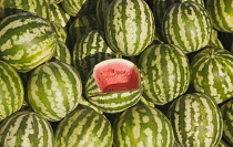 Turkey, Aydin Province, Kusadasi, Fresh watermelon on sale at town produce market with central fruit cut open to show red flesh and seeds.