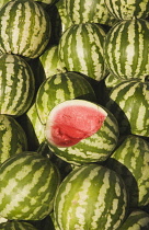 Turkey, Aydin Province, Kusadasi, Fresh watermelon on sale at town produce market with central fruit cut open to show red flesh and seeds.