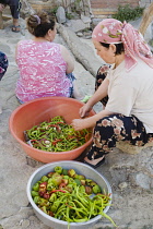 Turkey, Aydin Province, Sirince, Women preparing red and green chilies outside, in late afternoon sunshine in the old town.