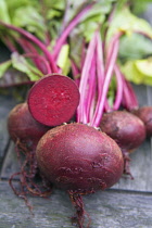Beetroot, Beta vulgaris, fresh Beets on wooden table, one with section cut through.