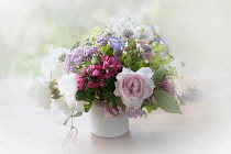 Rose, Escallonia. Yarrow and Astrantia, bunch of cottage garden flowers in a white jug with a dreamy white vignette.