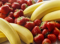 Banana, Musa acuminata, Two bunches with strawberries  grouped between.