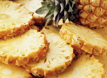Pineapple, Ananas comosus, One whole fruit and several slices with skin laid out.