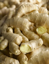 Ginger, Zingiber officinale, Overhead view of several pieces of fresh root ginger laid on top of one another with a couple broken open.