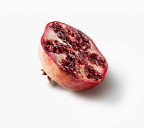 Pomegranate, Punica granatum, Side view of one fruit cut in half showing the juicy red seeds inside.