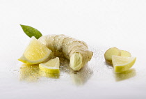Ginger, Zingiber officinale root with Lemon, Citrus limon,  pieces arranged on silver background, and spritzed with water. Selective focus.