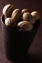 Nutmeg, Mace, Myristica fragrans, Mass of brown coloured spice in cup.