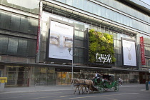 Germany, Berlin, Mitte, Vertical planting on the exterior of Galeries Lafayette on Friedrichstrasse with horse and carriage passing.
