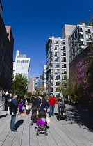 USA, New York, Manhattan, High Line linear park between buildings on a disused elevated railroad spur with people beside a wall painting by conceptual artist Ed Ruscha titled Honey I Twisted Through M...