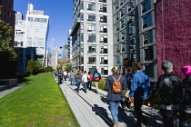 USA, New York, Manhattan, High Line linear park between buildings on a disused elevated railroad spur with people on a path beside the 23rd Street Lawn. USA, New York State, New York City.