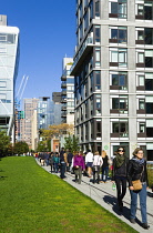 USA, New York, Manhattan, High Line linear park between buildings on a disused elevated railroad spur with people on a path beside the 23rd Street Lawn. USA, New York State, New York City.