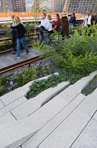 USA, New York, Manhattan, people walking among plants and old rails on the High Line linear park on an elevated disused railroad spur called The West Side Line beside the Hudson Rail Yards. USA, New...